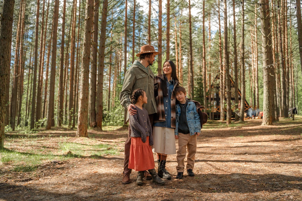 A family of four enjoys a peaceful vacation in a sunlit forest surrounded by tall pine trees.